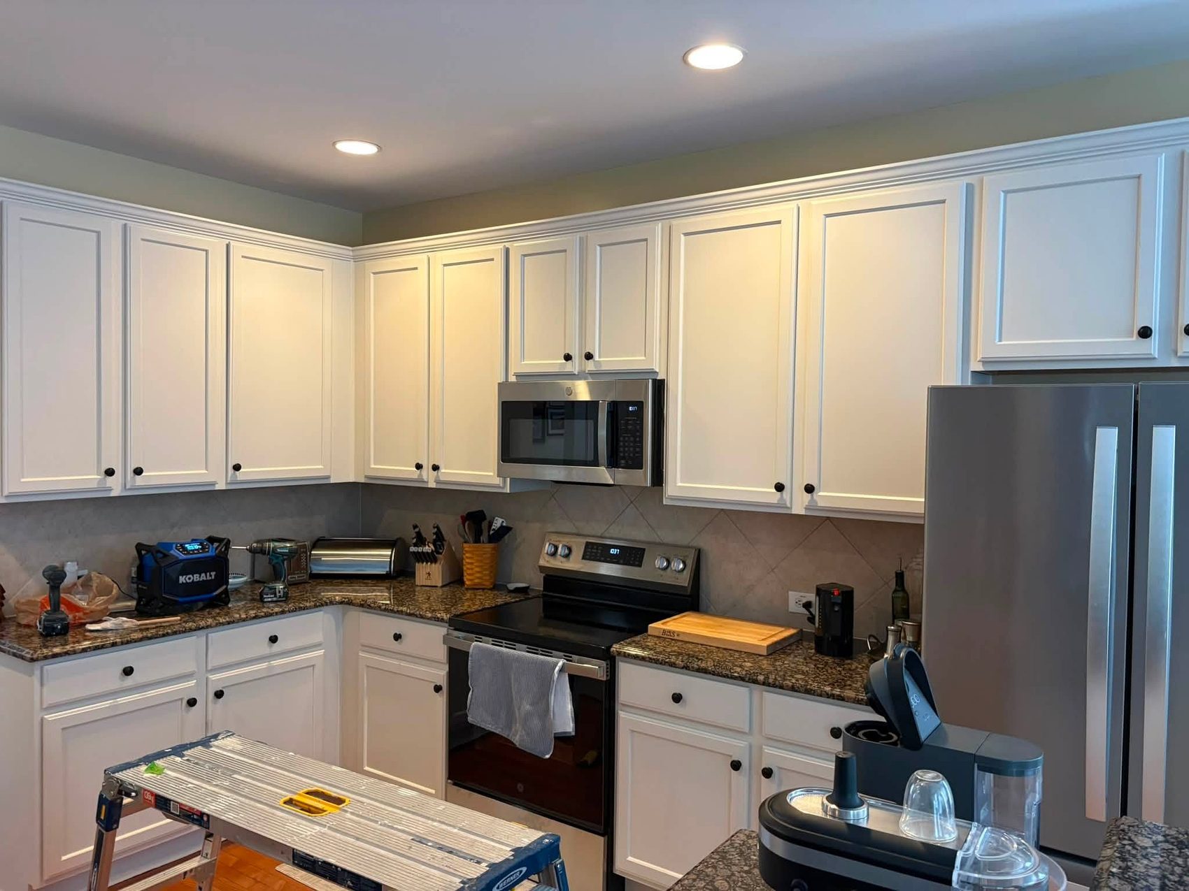 A kitchen part way through, cabinets going white by Carolina Superior Painting LLC